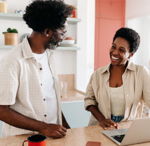 A couple smiling at each other in the kitchen